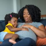 Pregnant black woman sitting with her daughter